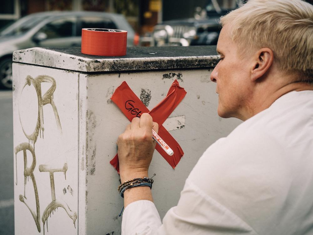 Julia Staron klebt bei einer Aktion für das Stadtmarketing Lünen beschriftete Kreuze auf einen Stromkasten